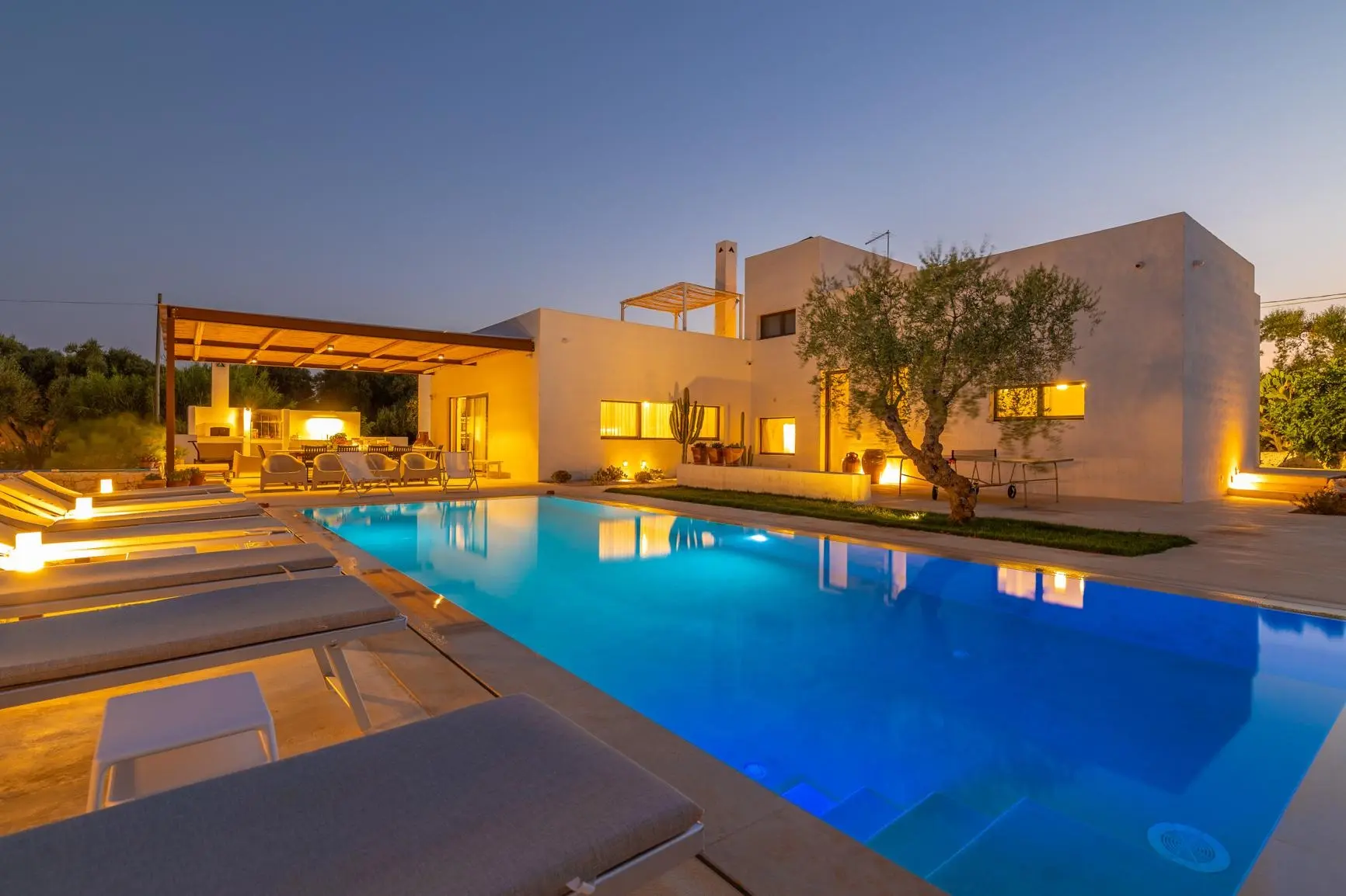 Villa di lusso con piscina illuminata al tramonto e ulivi, in vendita in Puglia